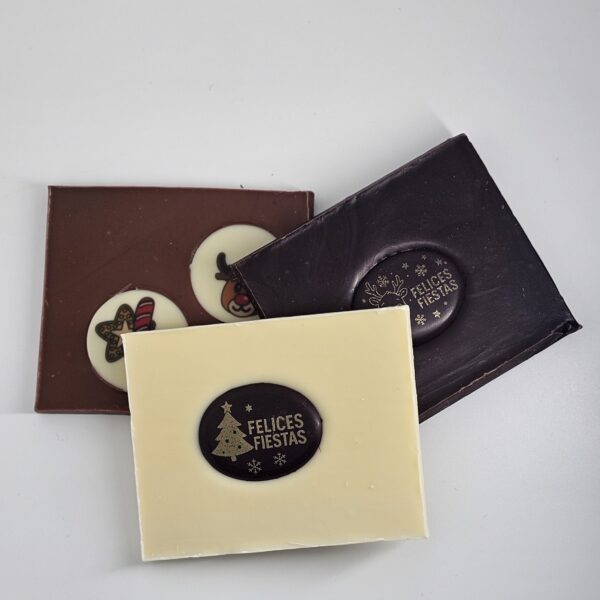 Tabletas navideñas de chocolate artesanal de Abuela Ili en versiones blanco, con leche y negro, con diseños de “Felices Fiestas” y motivos navideños.
