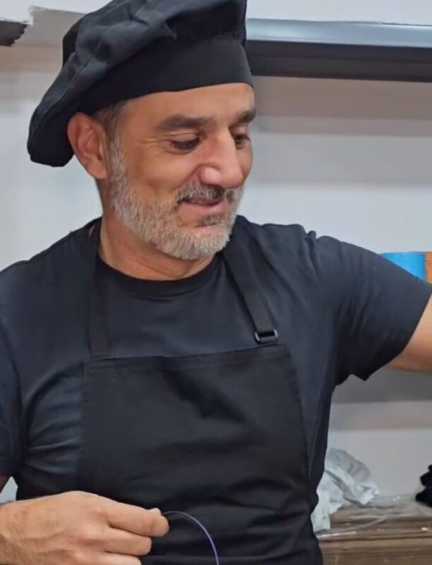 Le propriétaire d’Abuela Ili Chocolates présentant une tablette de chocolat artisanal dans la fabrique, valeur ajoutée de la marque.