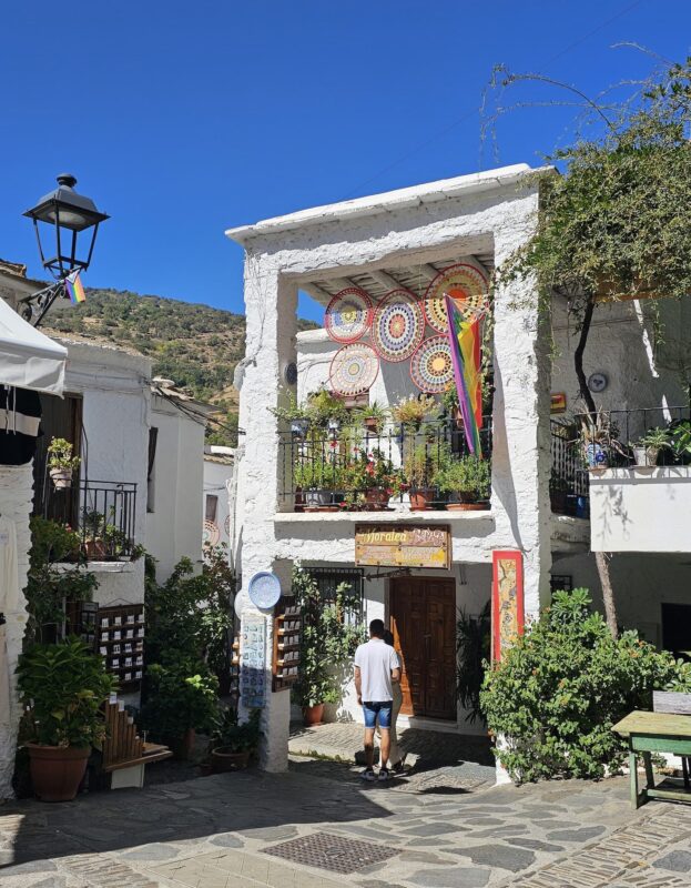 Calle típica de Pampaneira, en la Alpujarra granadina, con tinaos, flores y detalles artesanales bajo el sol.