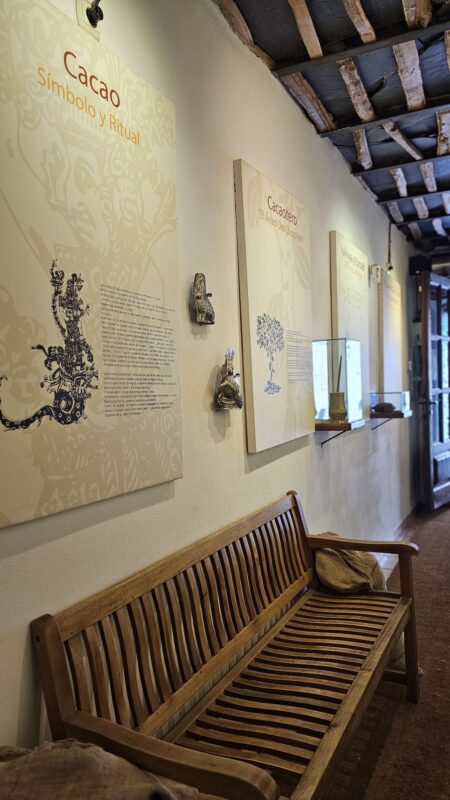Panel derecho del Museo del Chocolate Abuela Ili con información sobre el cacao y banca de descanso para visitantes.