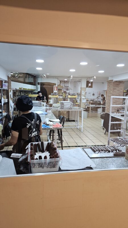 Vista desde el museo a través del cristal del personal y maquinaria de la fábrica de chocolate artesanal Abuela Ili.